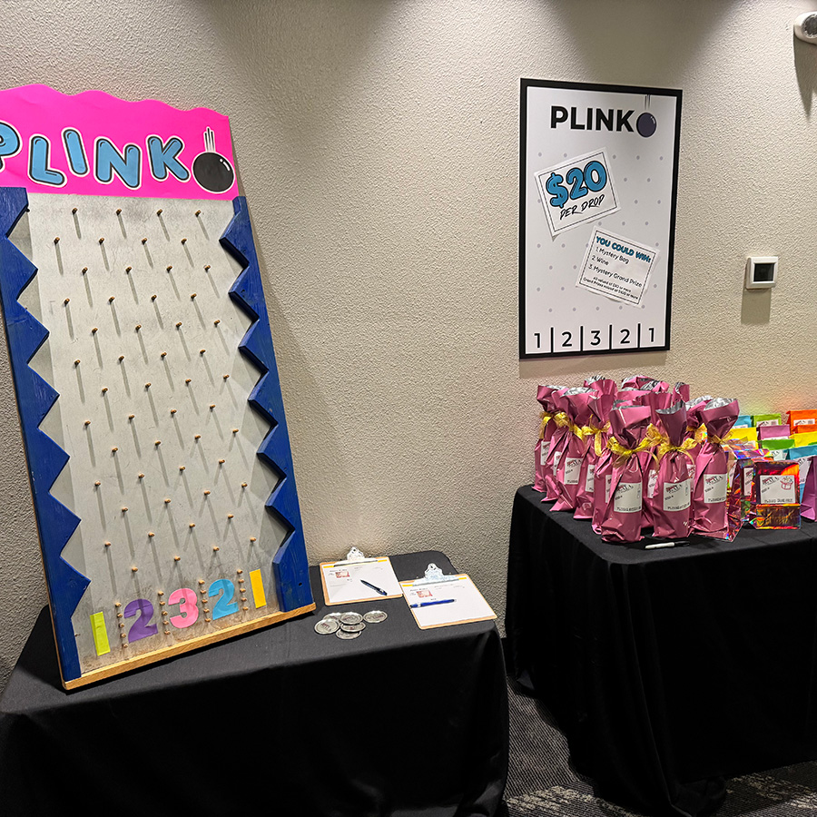 plinko mystery bag wine gala 2025 Plinko board next to wrapped wine bottles and mystery bags at 90s prom gala